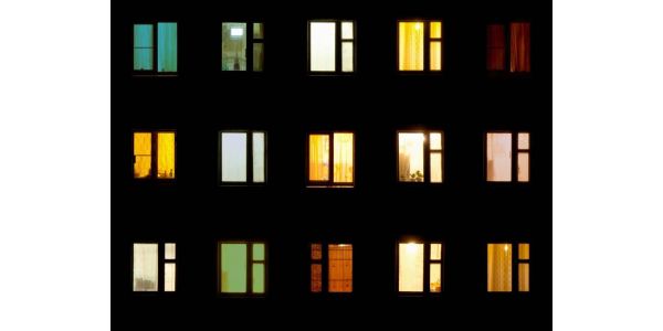 A multi-colored array of apartment building windows aglow at night