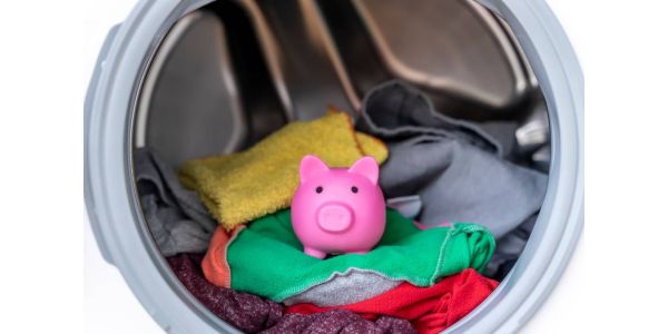 A pink piggy bank inside a washing machine atop a pile of clean clothes