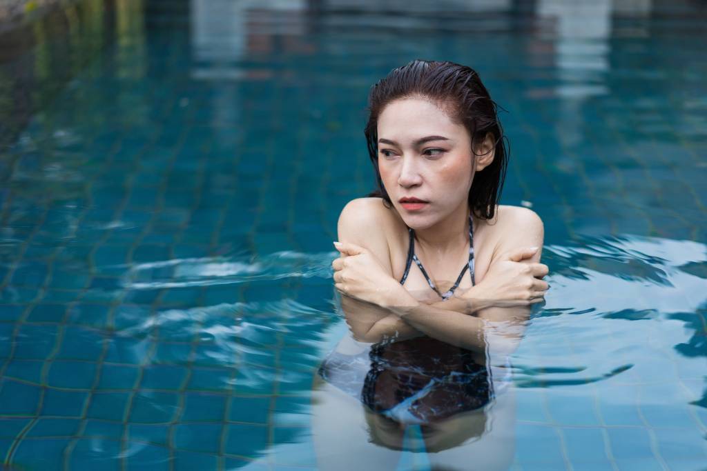 A shivering woman in a plunge pool looks off to the left.