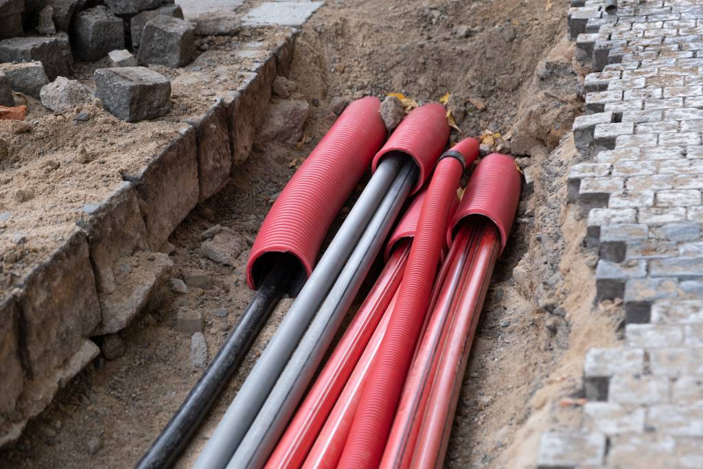 Electric and internet cables being buried beneath a cobblestone street.